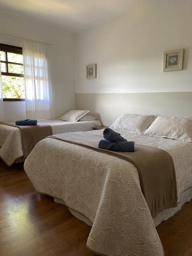 a bedroom with three beds with white sheets and a window at Casa dos Neves in Campos do Jordão