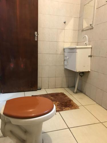 a bathroom with a toilet with a brown seat and a sink at CAPIVARI POUSADA B&B in Capivari