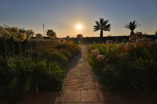 a path through a garden with flowers and a palm tree at Borgo della Luna in Birgi Vecchi