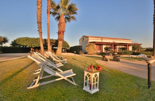 a row of lounge chairs on the grass with palm trees at Borgo della Luna in Birgi Vecchi