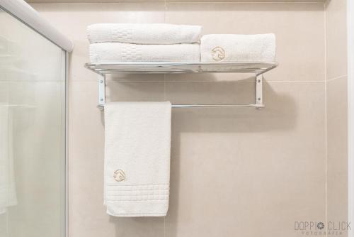 - Baño con toallero eléctrico y toallas blancas en Hotel Cavalinho Branco - Aptos 241 e 317, en Águas de Lindóia