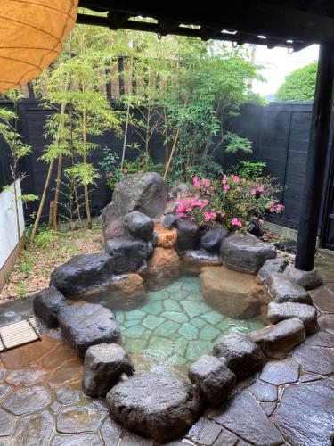 a small pond with rocks in a garden at Ryokan Mikasaya in Beppu