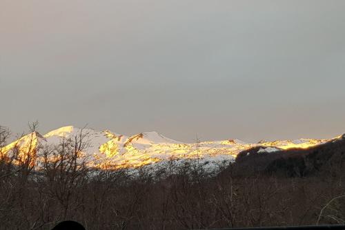 a snow covered mountain in the distance with snow on it at REFUGIO REHUE in Nevados de Chillan