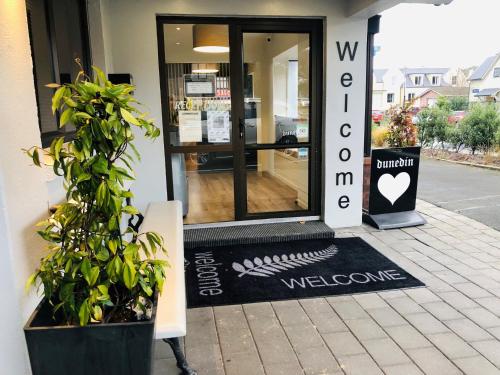 a door to a store with a welcome mat outside at Commodore Motel in Dunedin