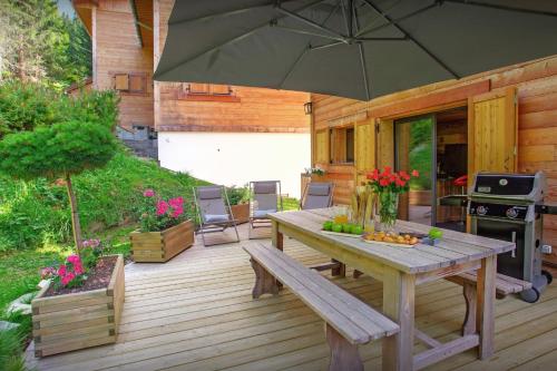 a wooden deck with a table and an umbrella at Chalet Charmar - OVO Network in La Clusaz