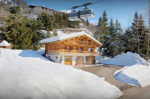una casa de madera en la nieve con un remonte en Chalet Le Mousqueton - OVO Network, en La Clusaz