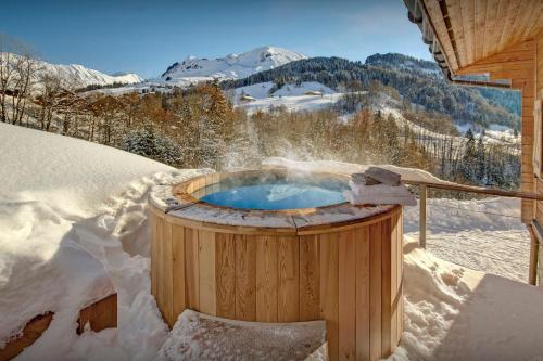 a hot tub covered in snow in a yard at Chalet des Mômes - OVO Network in Le Grand-Bornand