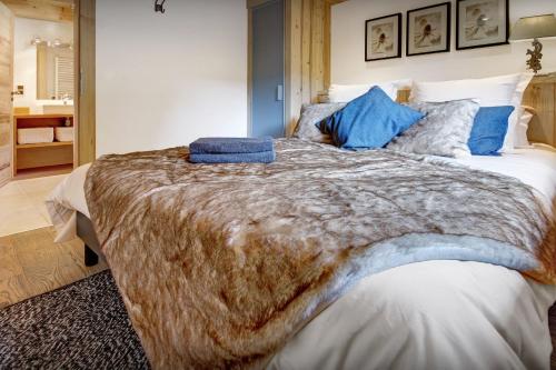 a bedroom with a large bed with blue pillows at Chalet de Paul et Marie - OVO Network in Manigod