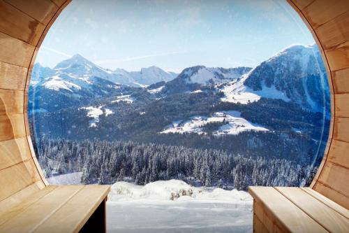 a round window with a view of a snowy mountain at La Grange à L'Ours - OVO Network in Manigod
