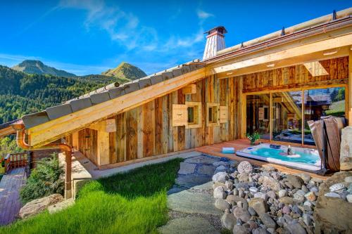 a large wooden house with a swimming pool at Chalet Les Brévins - OVO Network in Manigod