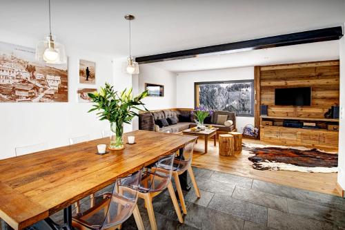 a living room with a large wooden table and chairs at Chalet La Frasse - OVO Network in La Clusaz