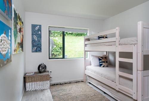 a bedroom with two bunk beds and a window at Miro Magic - Stay Waiheke in Palm Beach