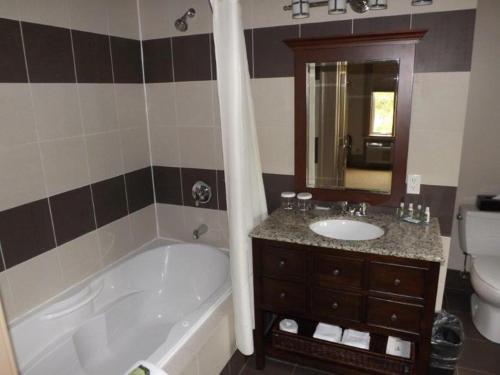 a bathroom with a tub and a sink and a toilet at The White House in Perth