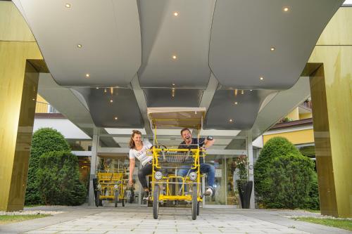 a man and woman riding in a yellow rickshaw at Johannesbad Hotel Palace - Kinder bis 11 kostenfrei in Bad Hofgastein