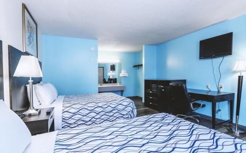 a hotel room with two beds and a desk with a computer at Blue Way Inn & Suites Wellington in Wellington