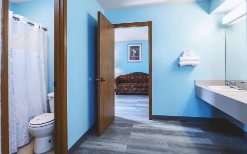 a bathroom with blue walls and a toilet and a sink at Sky-Palace Inn & Suites Wellington in Wellington