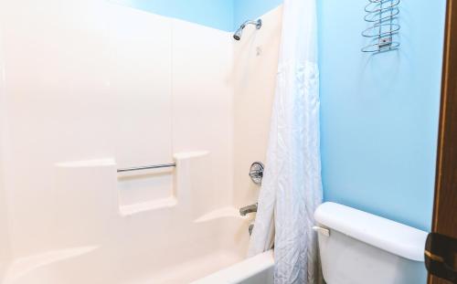 a bathroom with a white tub and a white shower curtain at Blue Way Inn & Suites Wellington in Wellington