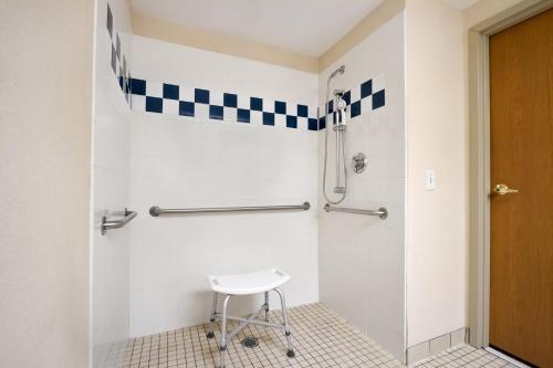 a bathroom with a shower with a stool at Ramada by Wyndham SeaTac Airport in SeaTac