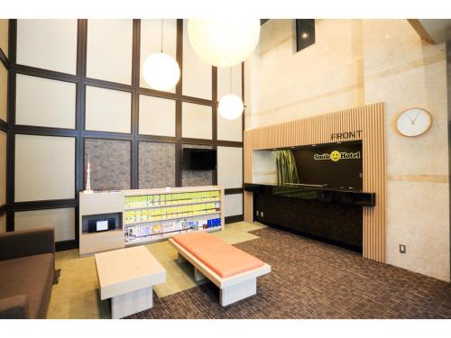een lobby met een wachtruimte met een klok aan de muur bij Smile Hotel Asakusa in Tokyo