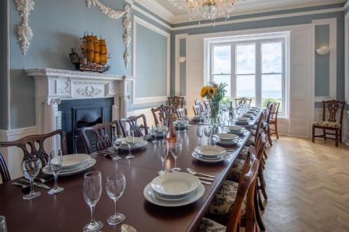 a dining room with a long table with chairs and a fireplace at Penally Manor - Luxurious Manor House - Tenby in Penally