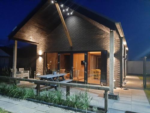 a brick house with a patio and a table at Vakantievilla 10 km van strand honden welkom omheinde tuin sauna buitenbad in Dirkshorn