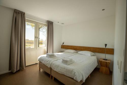 1 dormitorio con 1 cama con sábanas blancas y ventana en Spitsbroek, en Eede