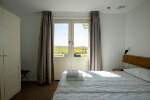 a bedroom with a bed and a large window at Spitsbroek in Eede