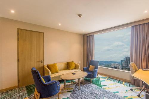 a hotel room with a couch and chairs and a large window at Holiday Inn Chandigarh Zirakpur by IHG in Chandīgarh