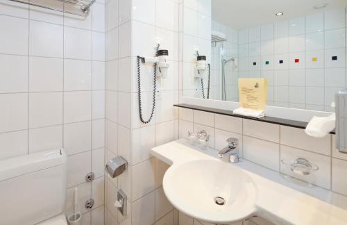a bathroom with a sink, toilet and bathtub at Hotel Metropol Basel in Basel