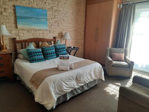 a bedroom with a bed with blue pillows and a chair at Fisant, Bokmakierie and Hoephoep Guest House in Bethlehem