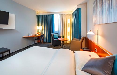バーゼルにあるHotel Metropol Baselのベッドとリビングルームが備わるホテルルームです。