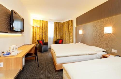 a hotel room with two beds and a desk at Hotel Metropol Basel in Basel