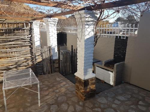 a patio with a brick fireplace and a chair at Crane Cottage in Colesberg