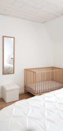 a white bedroom with a crib and a mirror at Gîte Lucian Mont-saint-michel in Moidrey