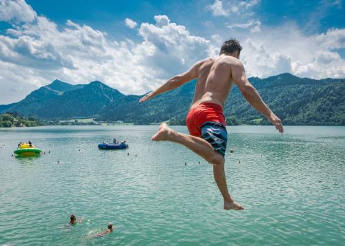 een man springend in het water bij een meer bij Landhaus SeenSucht in Schliersee