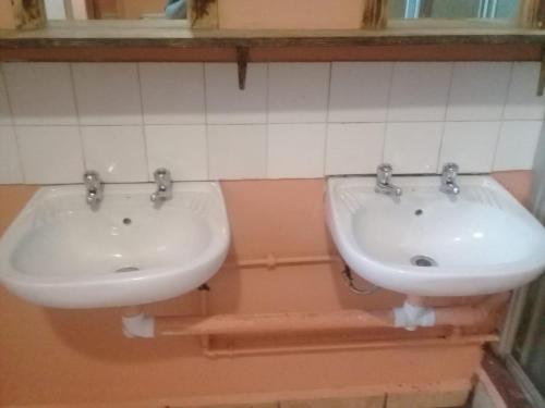 a bathroom with two white sinks in a room at Dirkie Uys Backpackers in Durban