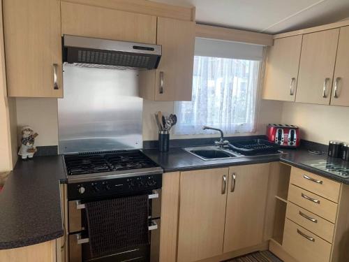 a kitchen with a stove and a sink at Serendipity Caravan Hire in Chapel Saint Leonards