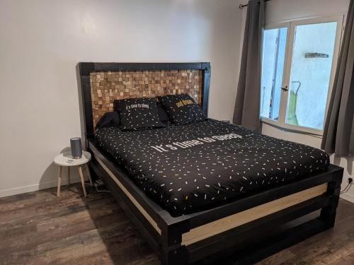 - une chambre avec un lit noir et une fenêtre dans l'établissement Maison dans quartier calme, à LʼIsle-sur-la-Sorgue