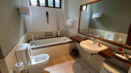 
a bathroom with a toilet, sink, and bathtub at Pinewood Beach Resort and Spa in Diani Beach
