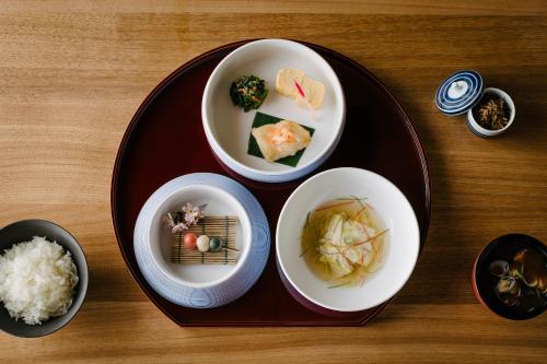 a plate with three bowls of food on a table at Nazuna Kyoto Gosho in Kyoto