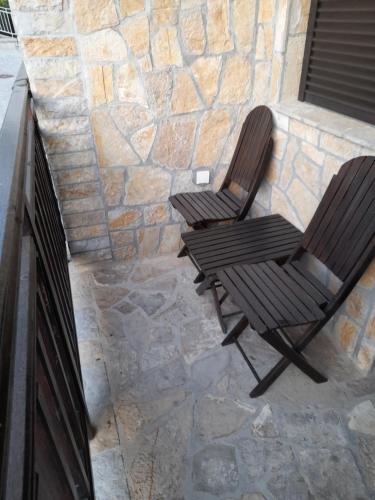 2 Stühle auf einer Terrasse mit einer Steinmauer in der Unterkunft Zlatibor Katarina apartman in Zlatibor
