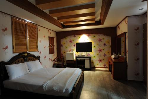 a bedroom with a bed and a desk and a television at Galleria Hotel in Andong