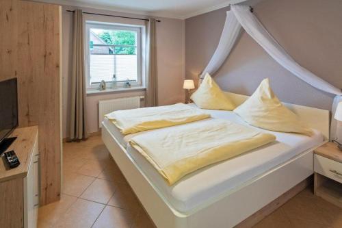 ein Schlafzimmer mit einem Bett mit gelben Laken und einem Fenster in der Unterkunft Ferienwohnung Ambiente in Norddeich