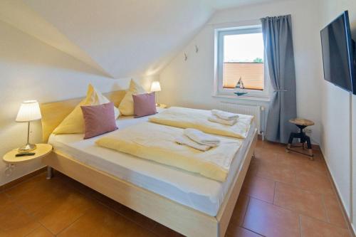 Cette chambre comprend un grand lit et une fenêtre. dans l'établissement Fewo-Sonnenplatz-30-Norddeich, à Norddeich