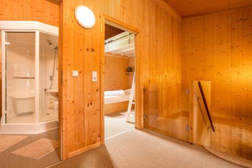 uma casa de banho com paredes com painéis de madeira e uma porta de vidro em Chalet Sternwarte em Hohentauern