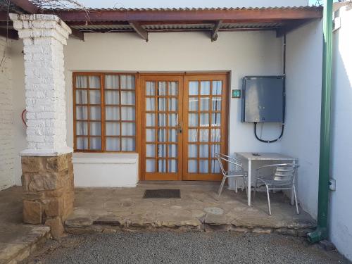 a patio with a table and chairs and a television at Crane Cottage in Colesberg