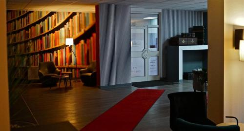 a library with bookshelves and chairs and a red rug at Rothenberger in Chemnitz