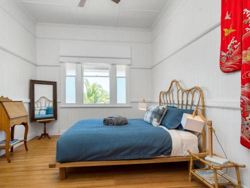 um quarto com uma cama azul e uma cabeceira em madeira em The Hideout House em Myocum