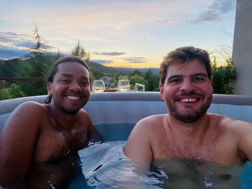 two men are sitting in a swimming pool at Maison des Monts Bleus in Saint-Roman-de-Tousque