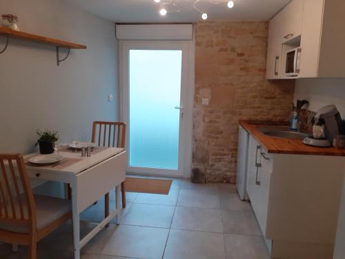 een keuken met een tafel, een wastafel en een deur bij Agréable studio à 5 mn à pied de la mer in Langrune-sur-Mer